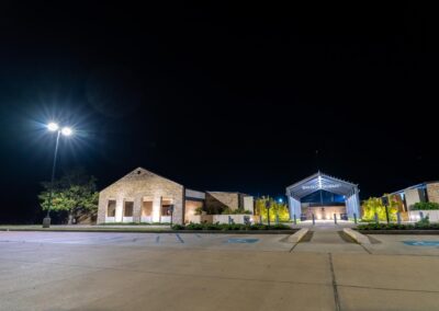A front view of the entrance of Bayou Academy and it's brightly lit street lights in the parking lot.